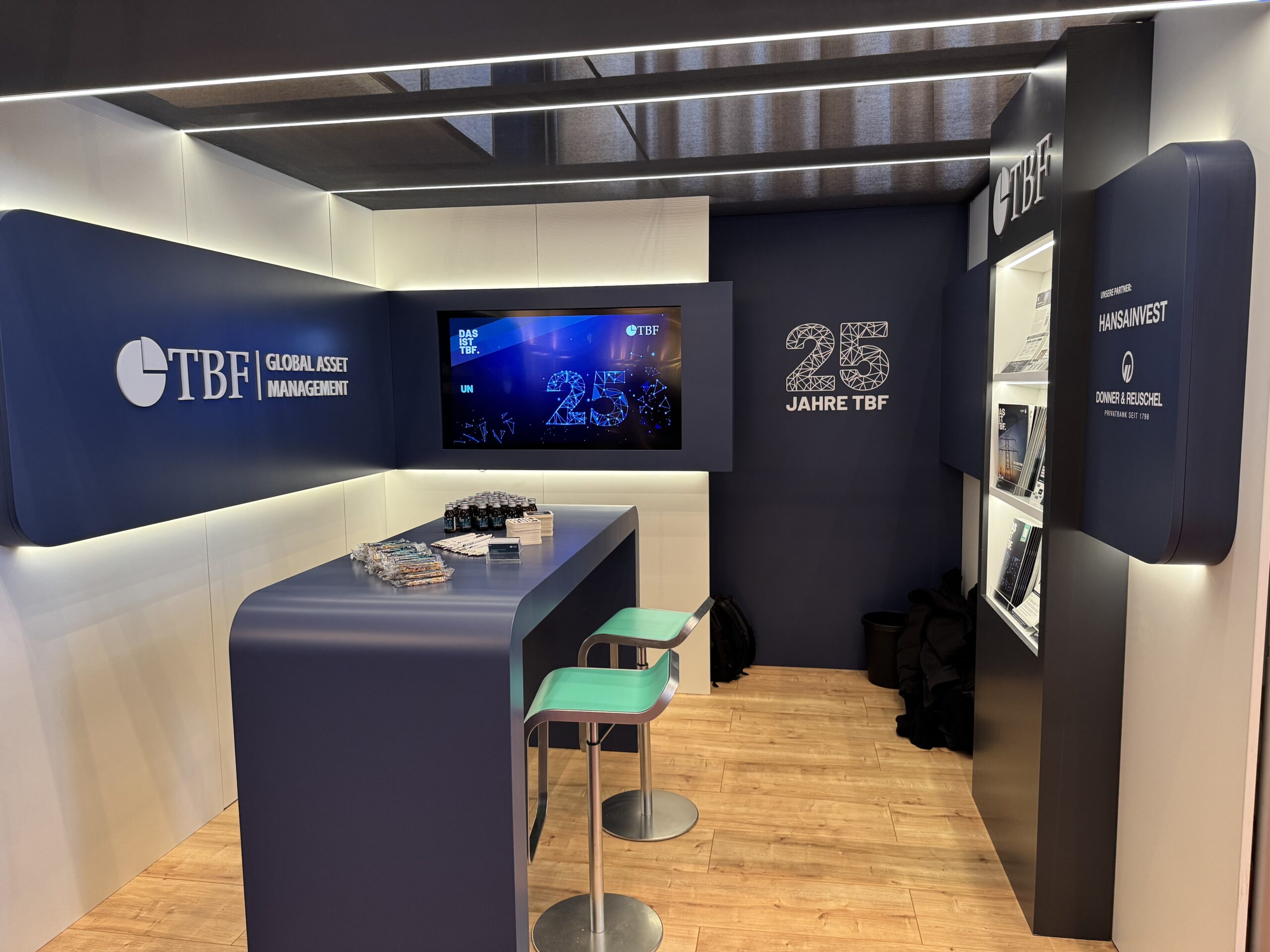 Das Bild zeigt den TBF Messestand in Mannheim. Mit Logo, Bildschirm und Werbematerial.