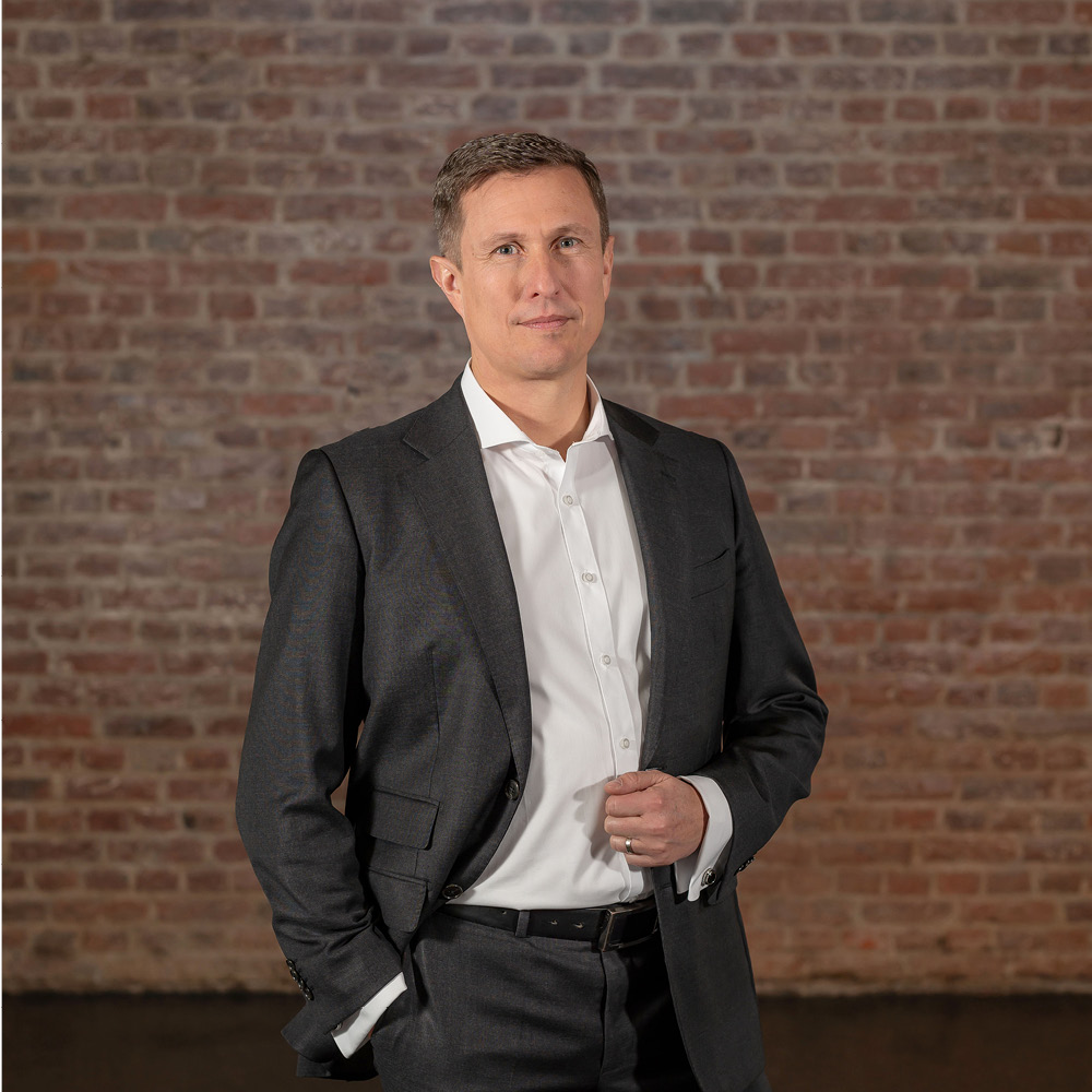 Das Bild zeigt TBF Sales and Marketing GmbH Geschäftsführer Dirk Zabel stehend vor einer Ziegelwand in Bad Homburg