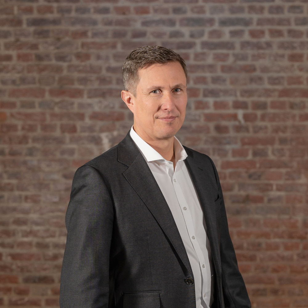 Das Bild zeigt TBF Sales and Marketing GmbH Geschäftsführer Dirk Zabel seitlich stehend vor einer Ziegelwand in Bad Homburg