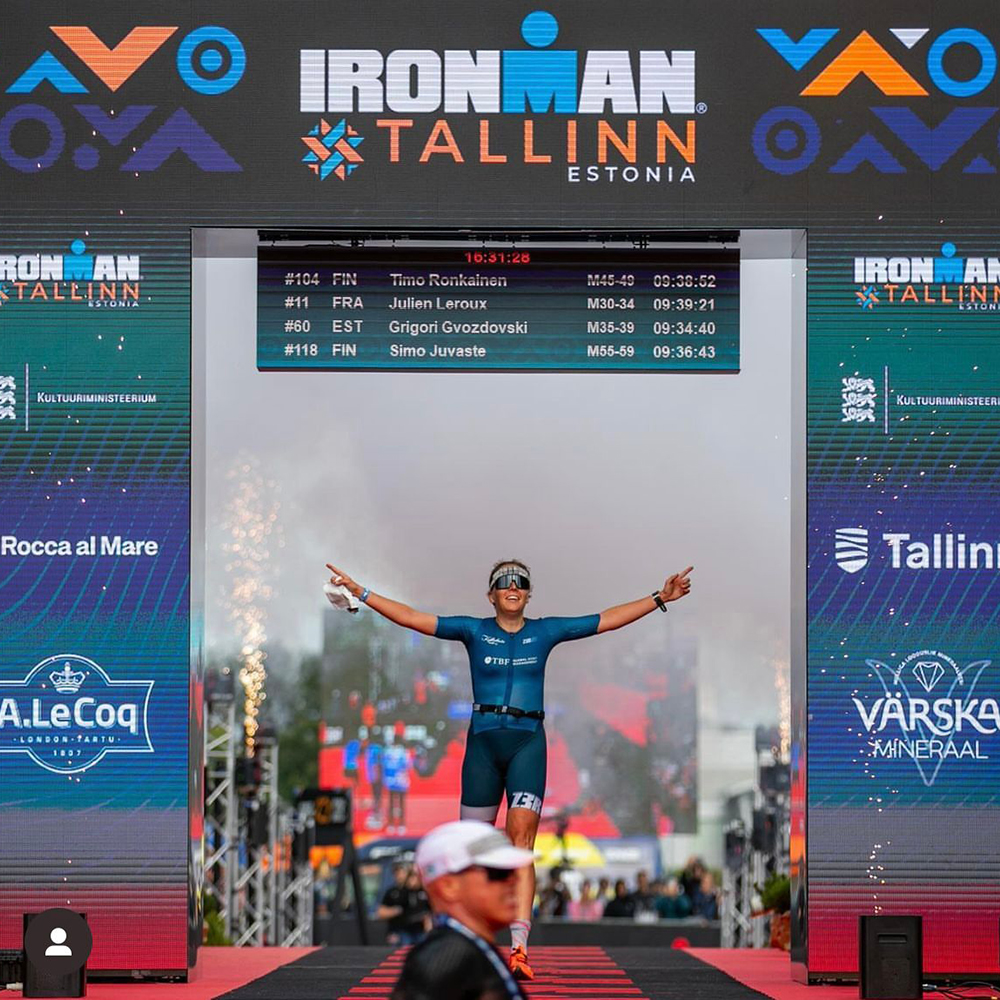 Das Bild zeigt Triathletin Sophia Trenz bei ihrem Sieg in Tallinn während sie mit erhobenen Armen ins Ziel läuft